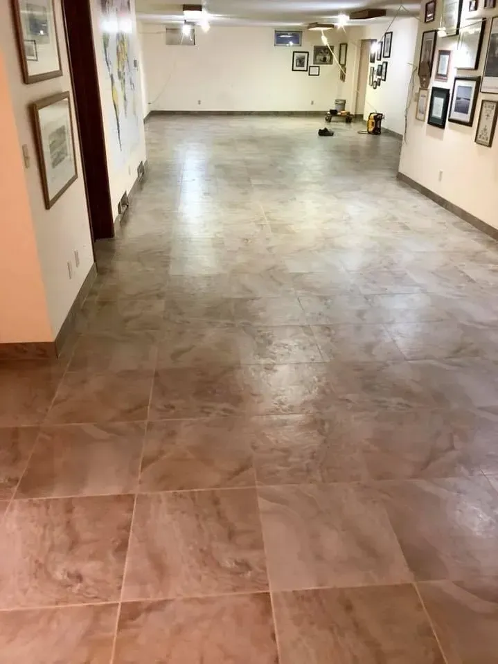 Long indoor hallway with polished tile floor, wall art, and ceiling lights