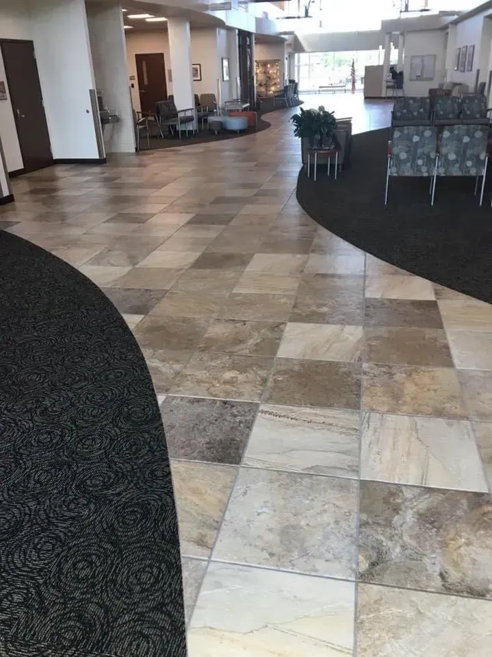 Hotel lobby with patterned tile floor, carpeted areas, and seating along the sides.
