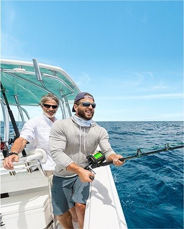 Two people fishing on a boat in blue ocean under a clear sky