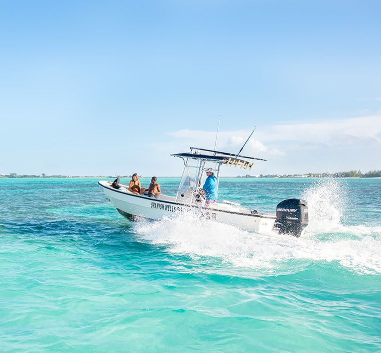 Small motorboat speeding across turquoise water under a bright blue sky, splashing spray behind it