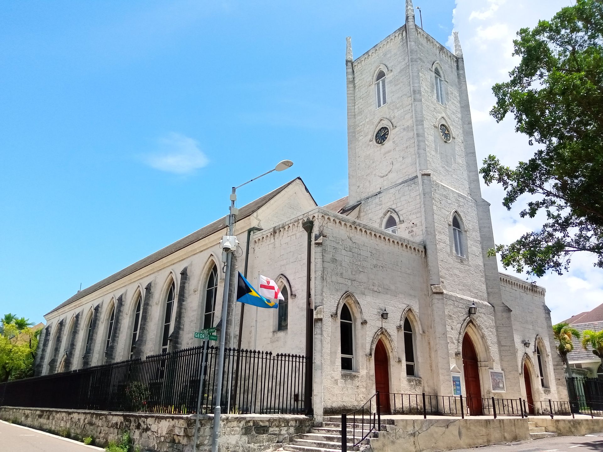 Stone church with a tall tower and arched entrance beside a street under a blue sky