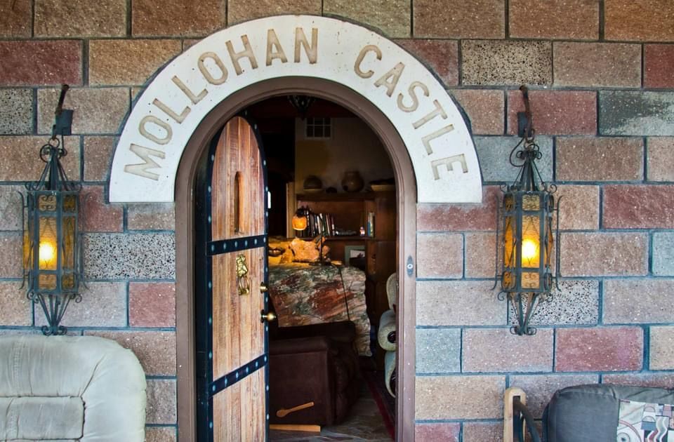 Stone archway entrance to Mollohan Castle with open wooden door.