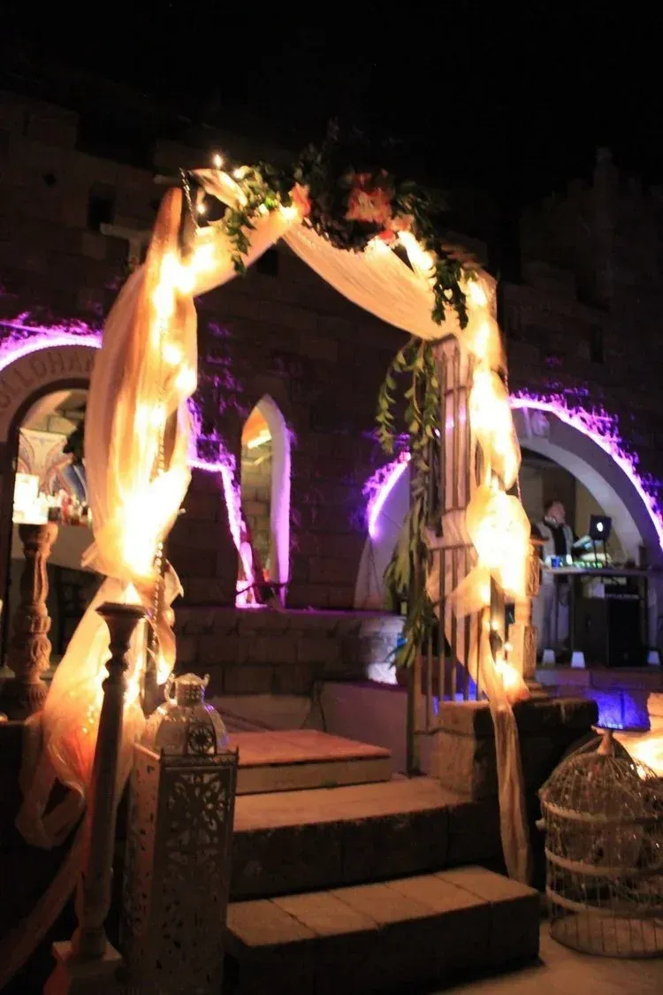 Archway decorated with lights and draped fabric over stone steps at night.