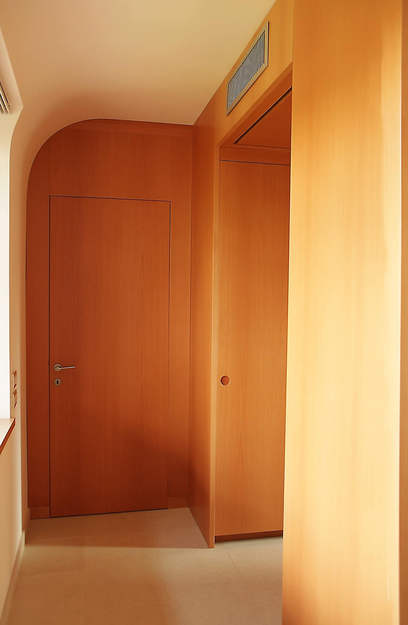 Stretto corridoio in legno con porte chiuse e pavimento beige