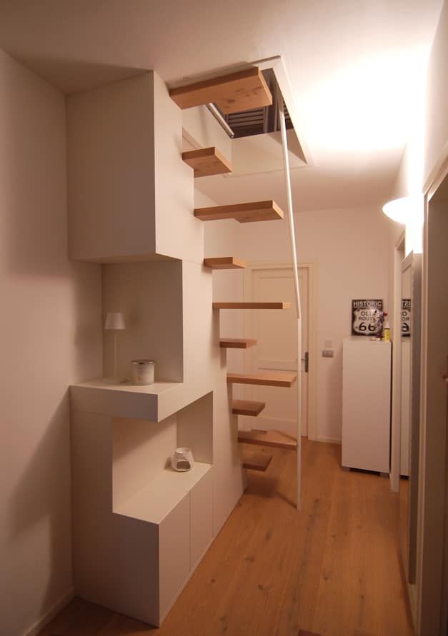 Corridoio moderno con scala a sbalzo in legno, pareti bianche e pavimento in parquet.