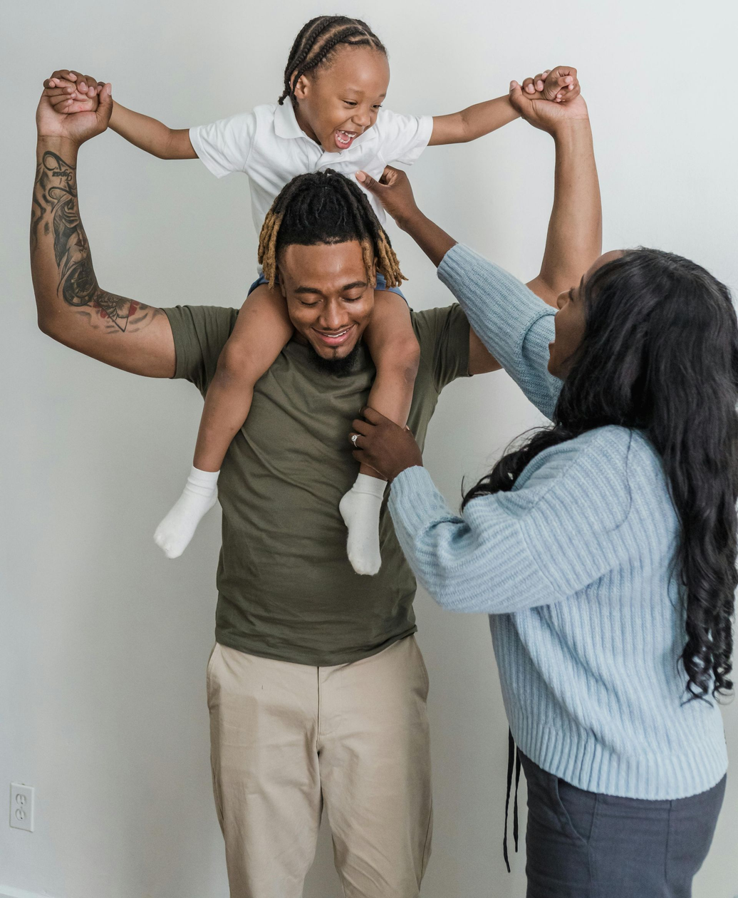 A family is sitting on the floor laughing and hugging each other.