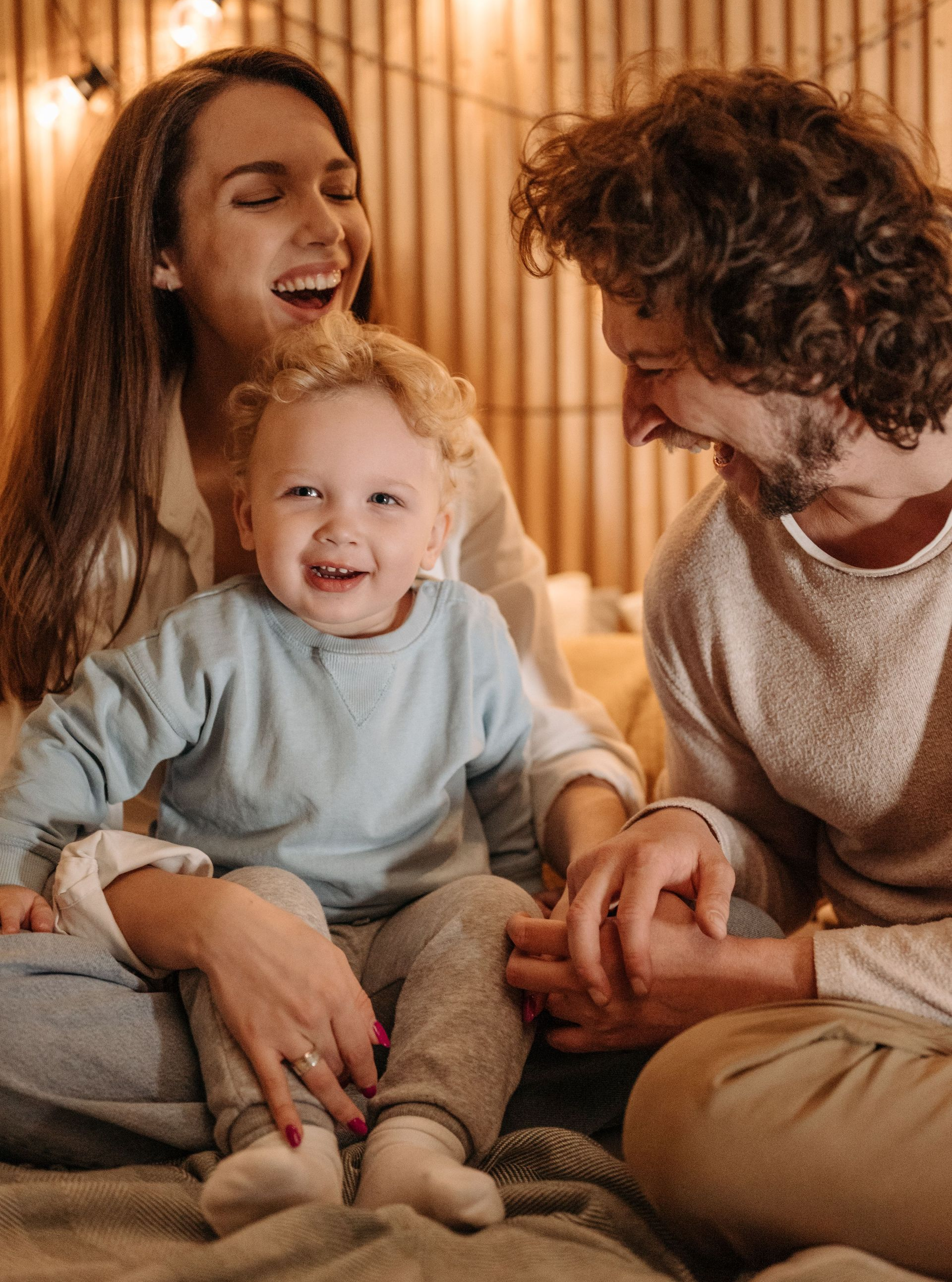 A family is sitting on the floor laughing and hugging each other.