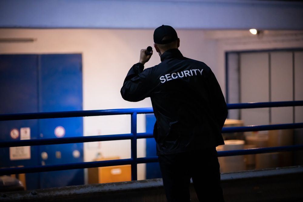 Security guard in black jacket using a radio on an indoor balcony at night