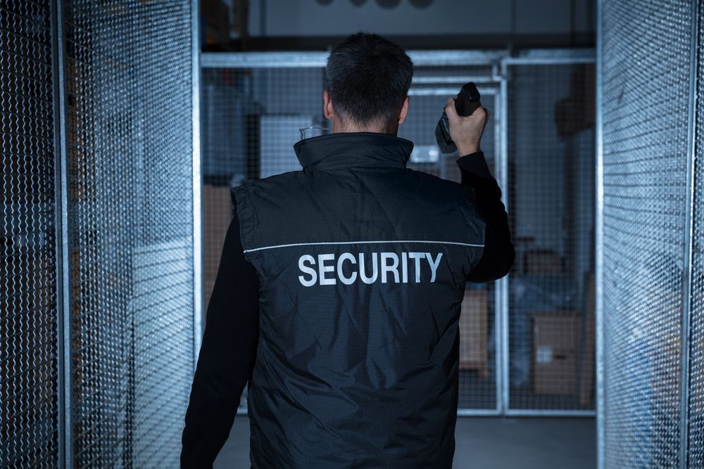 Security guard walking through a corridor with a walkie-talkie raised in a dim industrial building