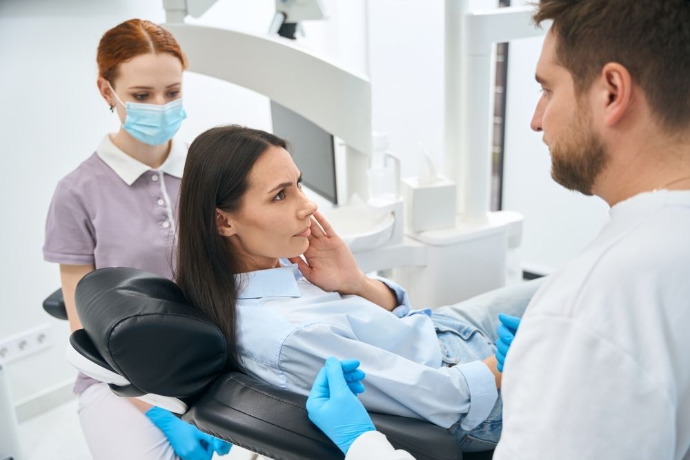 Patient with tooth pain in a dental chair showing common reasons to call an emergency dentist in Redlands CA