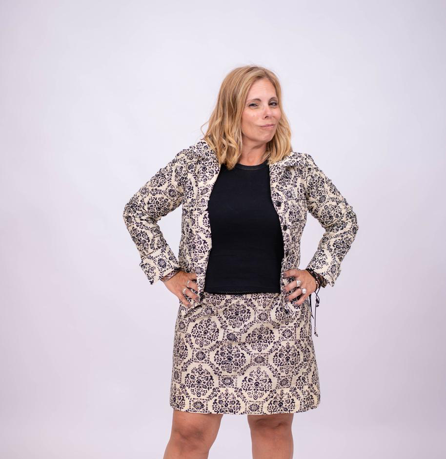 Mujer con traje estampado, con las manos en las caderas y sonriendo.
