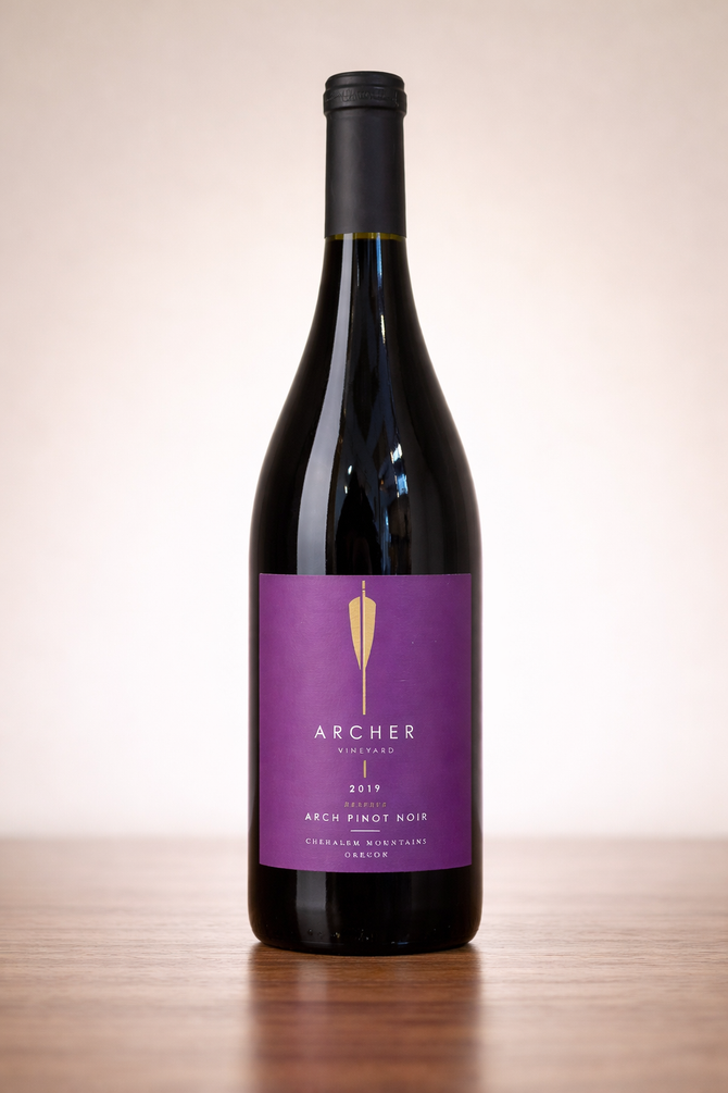 Purple-labeled wine bottle standing on a wooden surface against a plain background