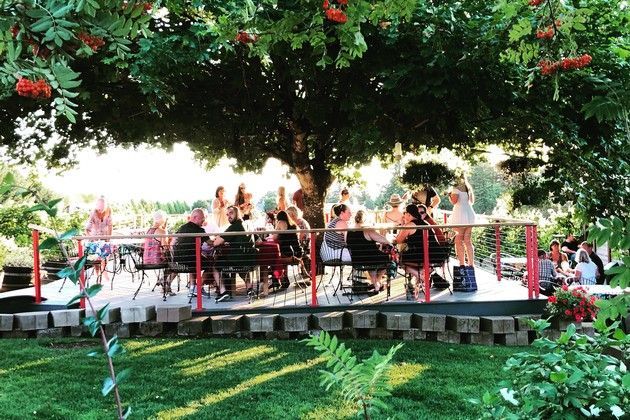 A group of people are sitting at tables under a tree.