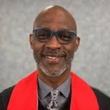 A man wearing glasses and a red scarf is smiling for the camera.