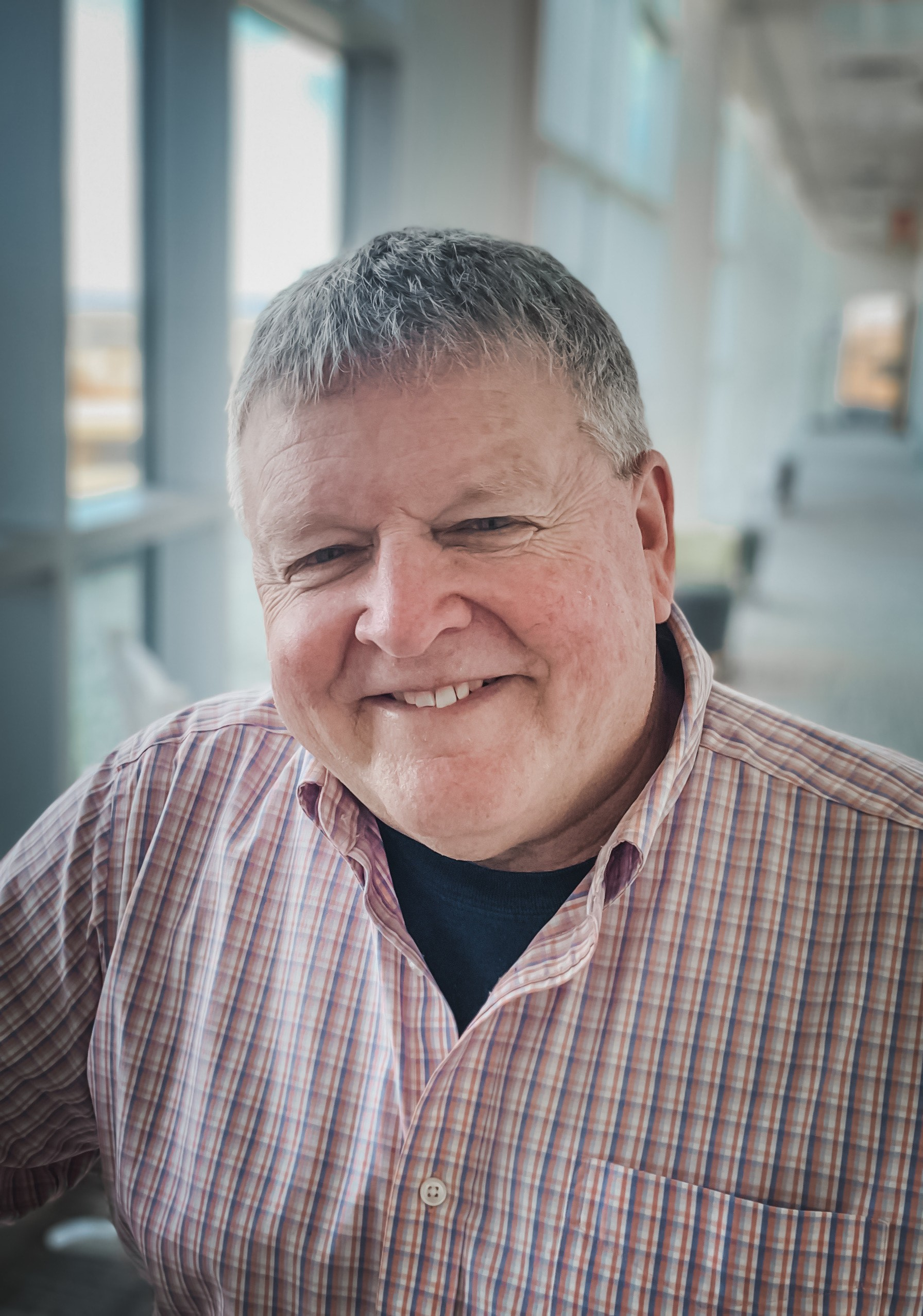 A man in a plaid shirt is smiling for the camera.