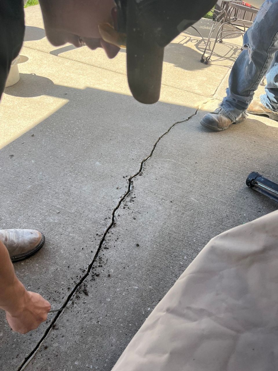 Cracked concrete ground between people’s legs, with a visible split running through the pavement.