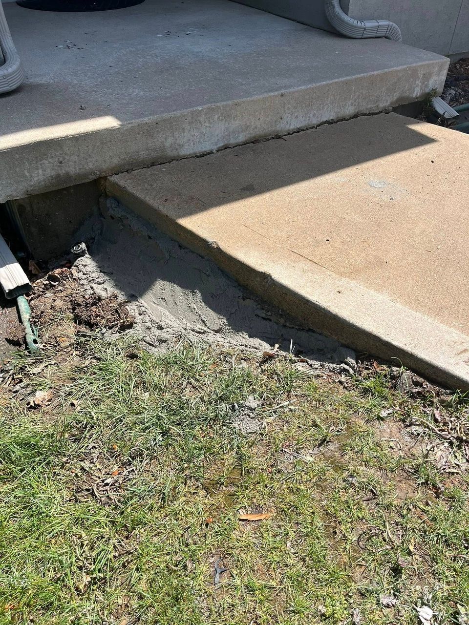 Concrete porch step with a sloped ramp beside it leading down to a grassy yard.