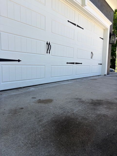 White garage door with black handles and arrows on a concrete driveway.
