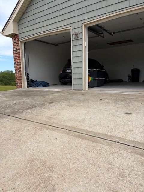 Two-car garage with open doors, a car parked inside, and a concrete driveway in front