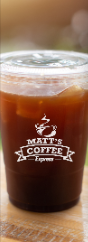 Iced coffee in a clear plastic cup with a Matt’s Coffee logo on a wooden table