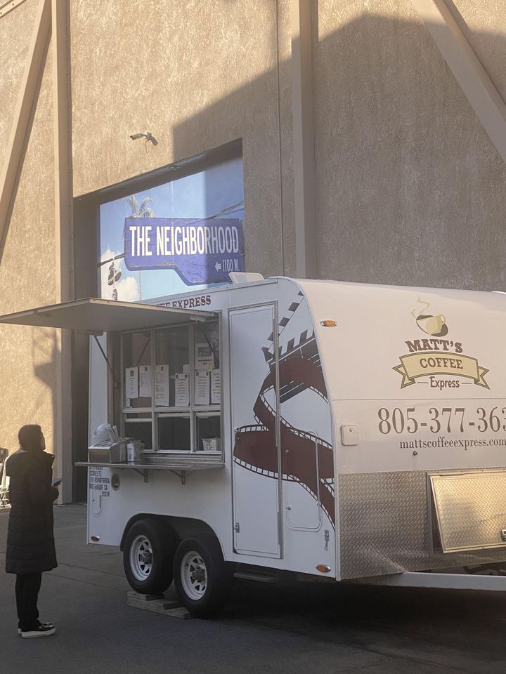 Food truck parked outside a building, with a person standing nearby at the service window.