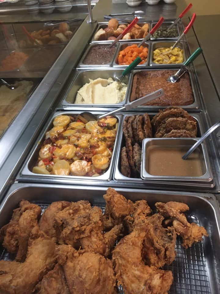 A buffet line with fried chicken and sides: potatoes, mashed potatoes, vegetables, and gravy.