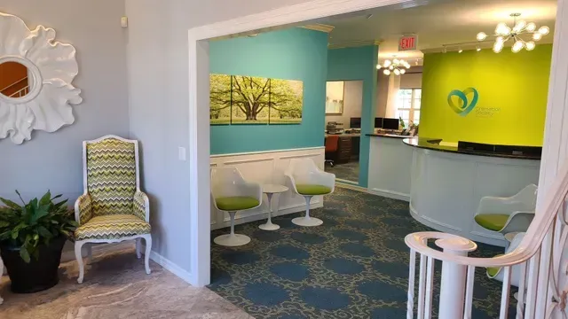 Modern medical waiting room with teal and lime accents, white chairs, and a reception desk