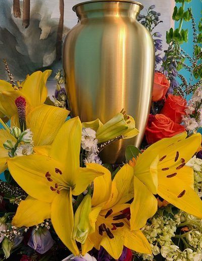 Yellow lilies and red flowers arranged around a gold urn centerpiece