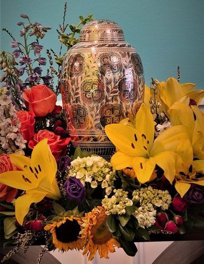 Colorful floral arrangement surrounding a polished silver urn or memorial vase