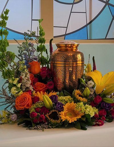 Autumn floral arrangement with colorful flowers around a copper urn centerpiece on a table