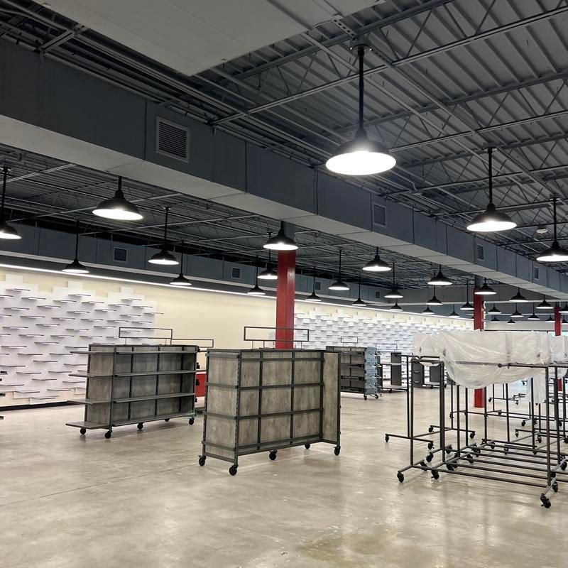 Empty warehouse with carts, metal shelving, and overhead industrial lights