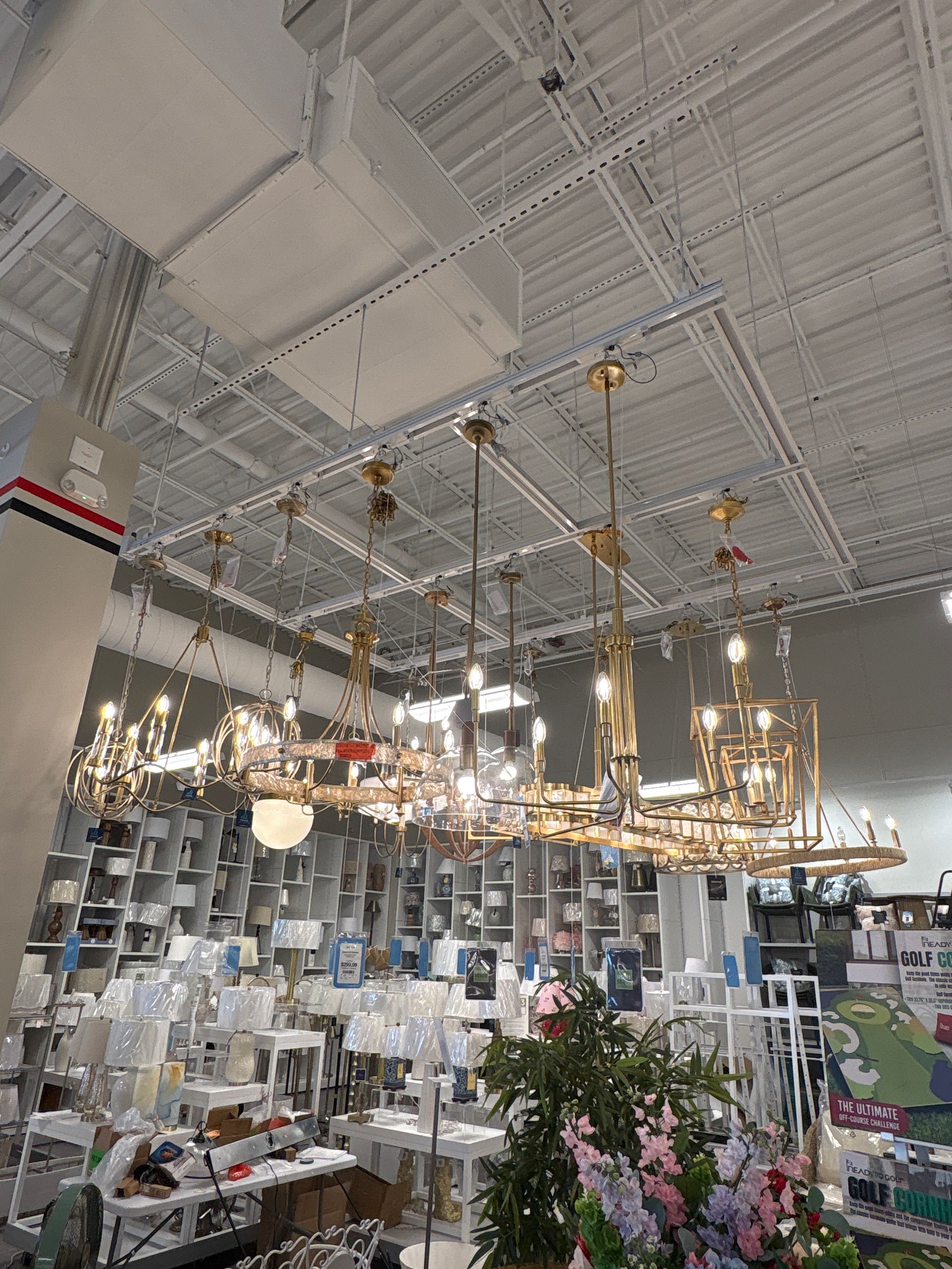 Bright showroom with hanging chandeliers, ceiling lights, and furniture displays