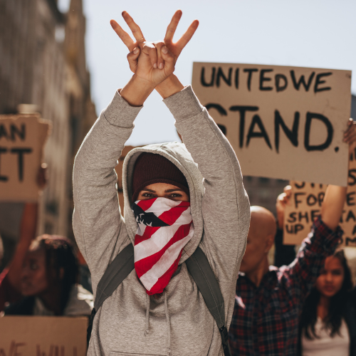 Protester with American flag bandana makes a V-sign in front of 