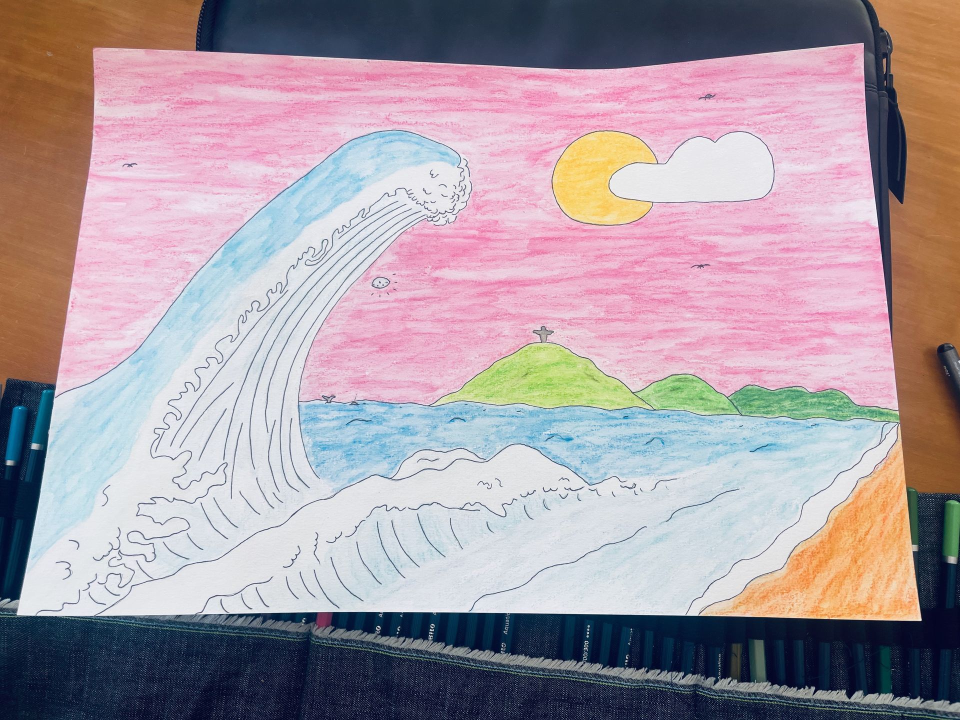 Tekening met kleurpotloden: grote oceaangolf, zon, wolk, strand, eiland, roze lucht.