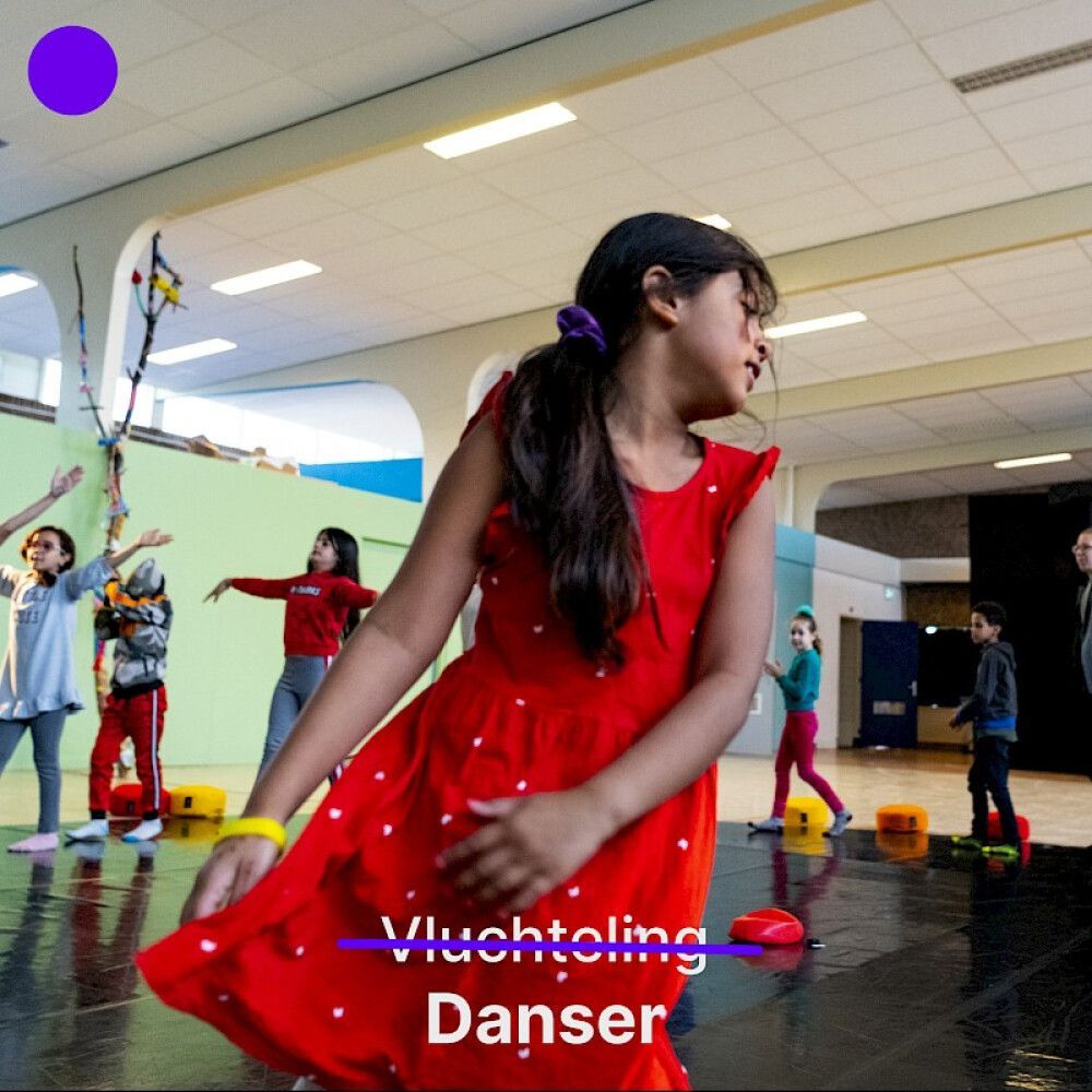 Meisje in rode jurk danst, andere kinderen op de achtergrond. Binnen, in een dansles.