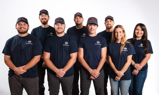 A group of people wearing blue shirts and hats are posing for a picture.