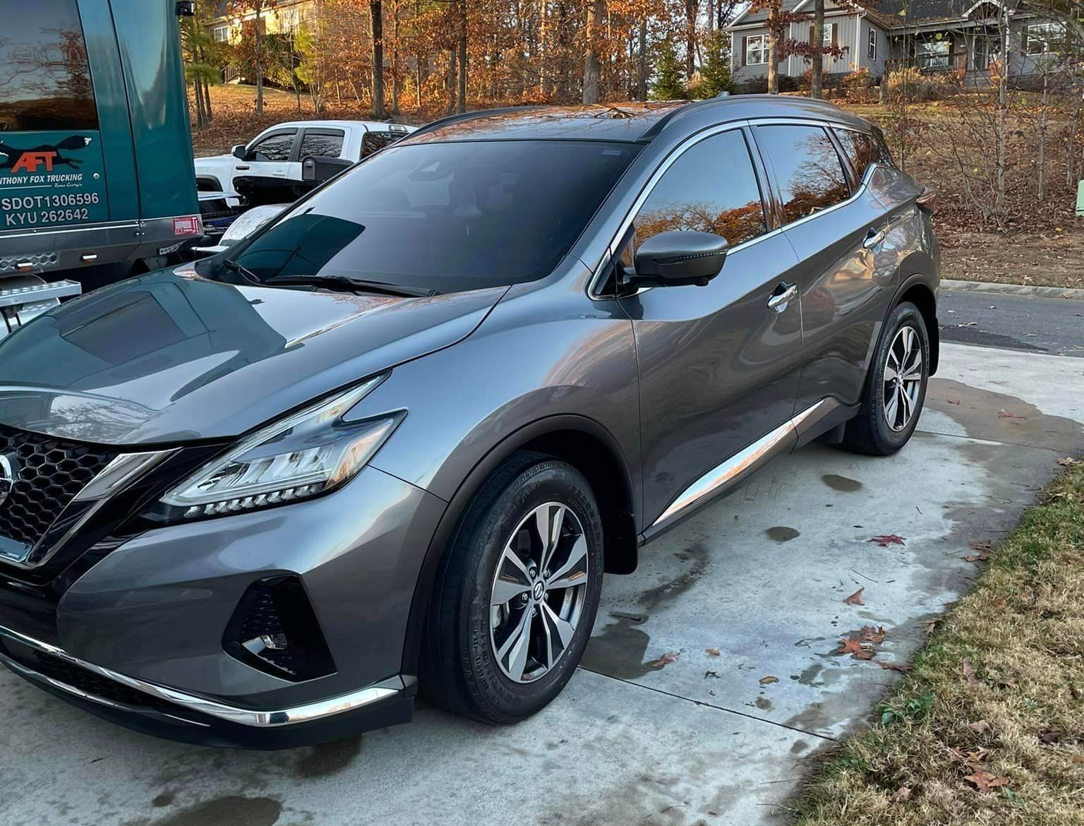 A gray nissan murano is parked on the side of the road.