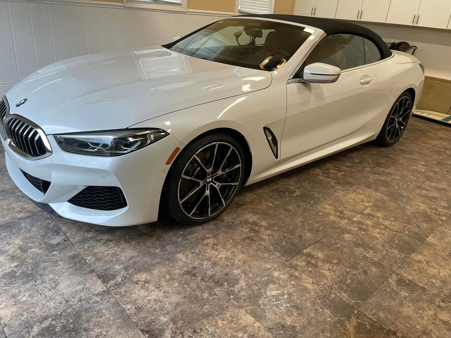 A white bmw 8 series convertible is parked in a garage.