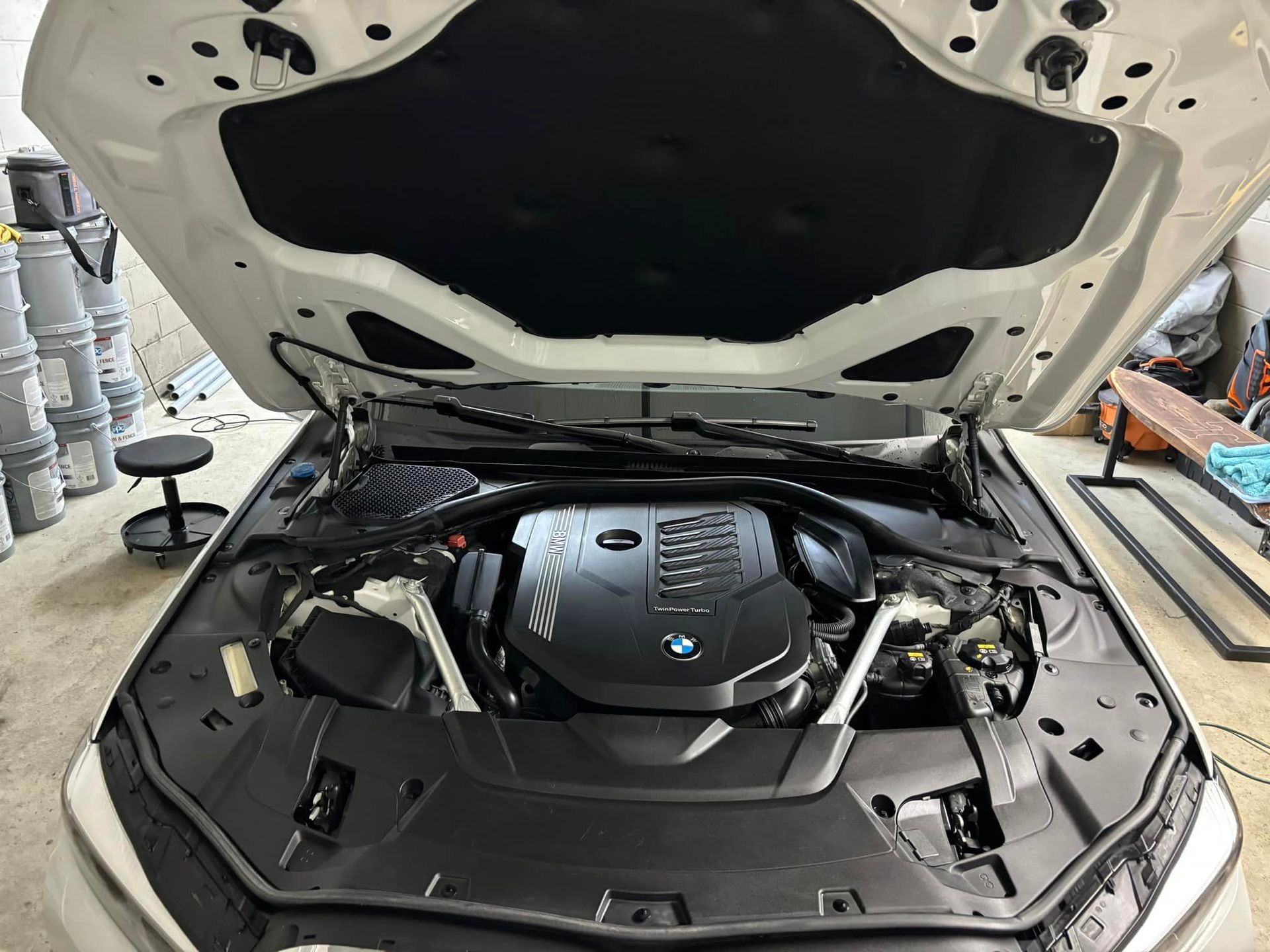 The engine of a white car is shown with the hood open.