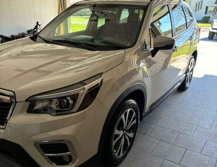 A white subaru forester is parked in a garage.
