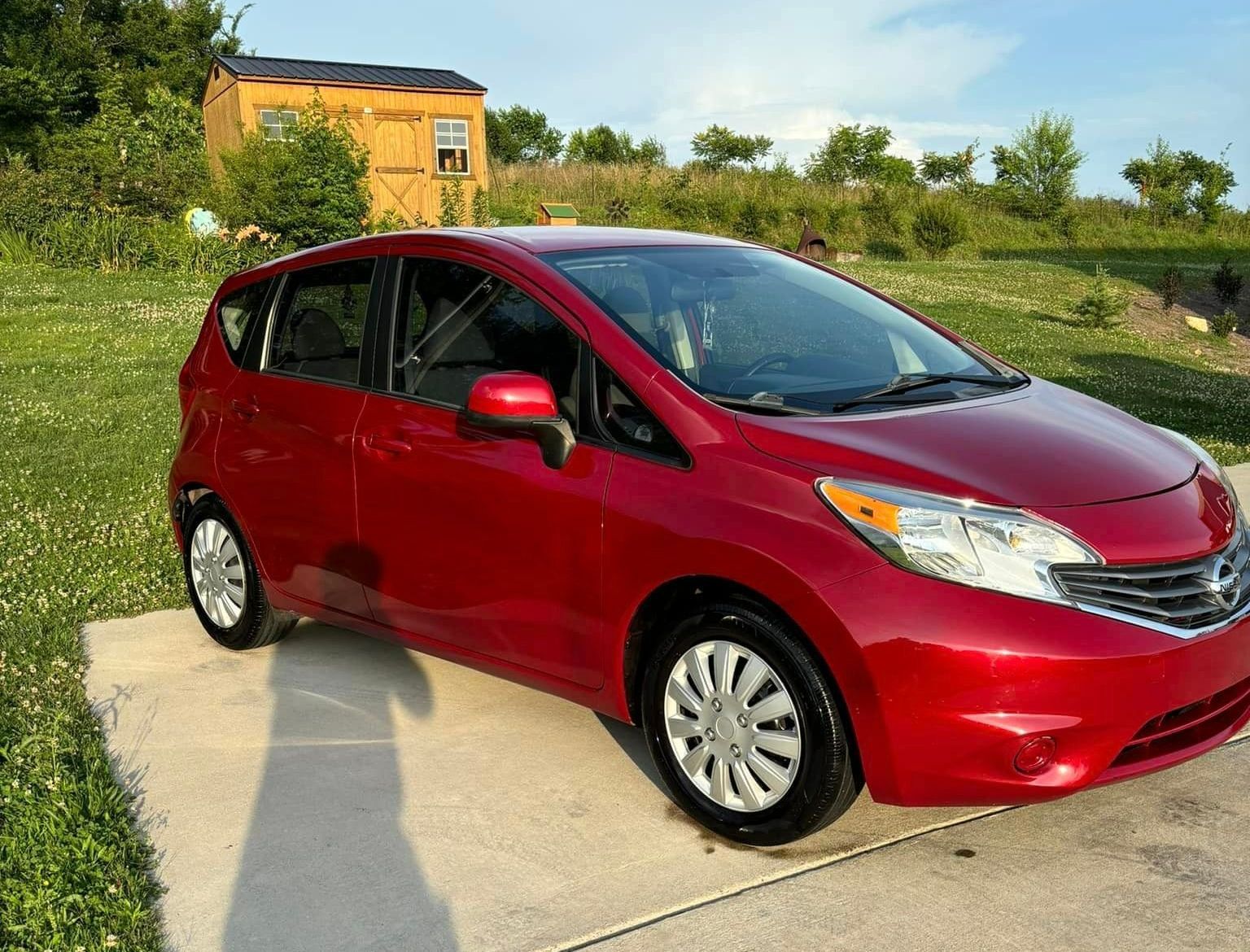 A red car is parked on a sidewalk in front of a house