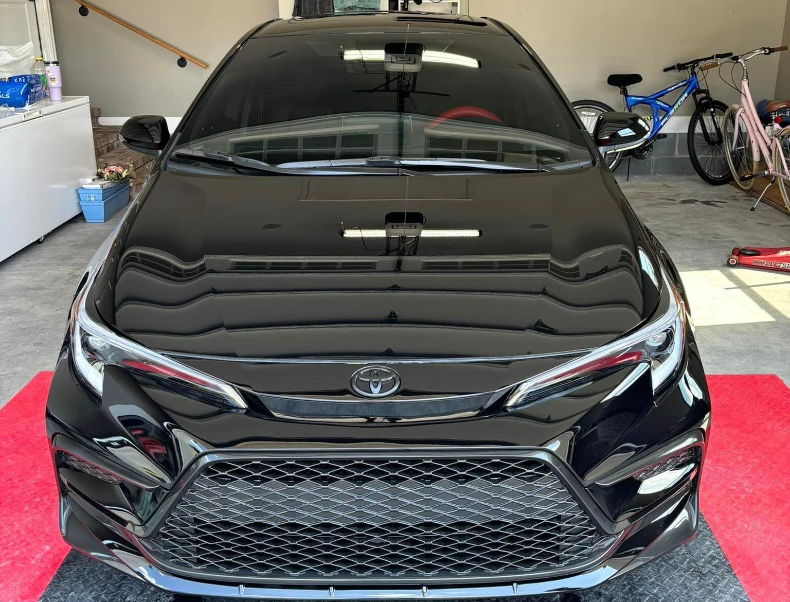 A black toyota corolla is parked in a garage. A black toyota corolla is parked in a garage.