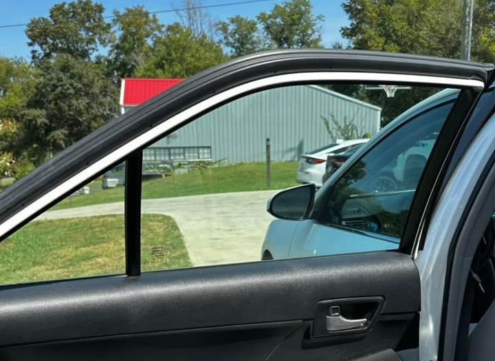 A car is parked in a driveway with a building in the background.
