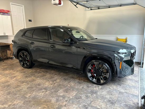 A gray suv is parked in a garage under a garage door.