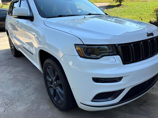 A white jeep grand cherokee is parked in a driveway.