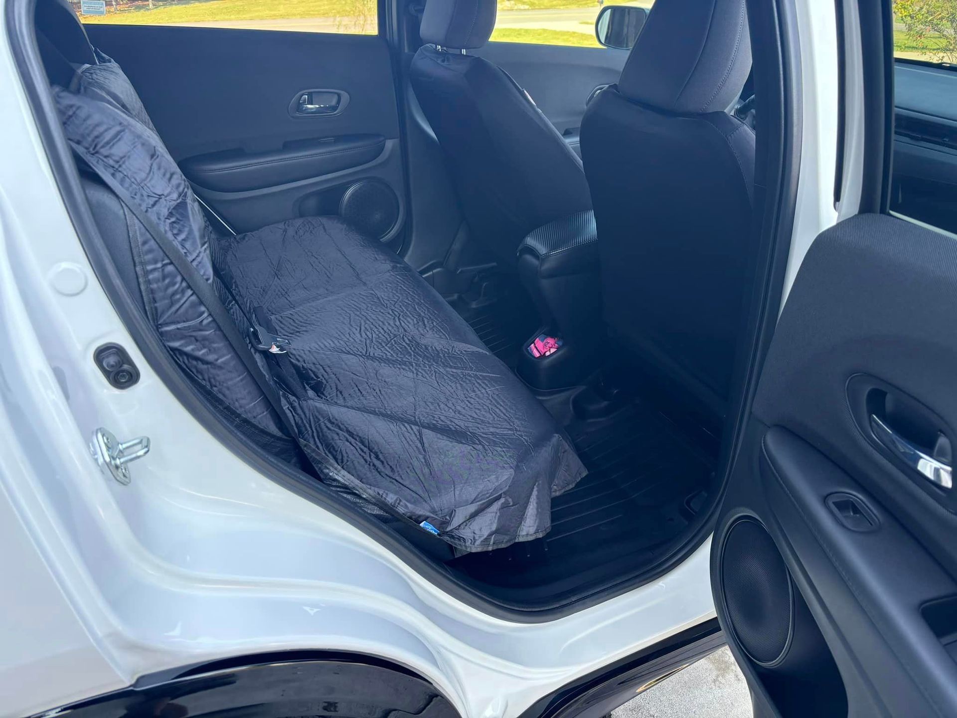 A golf bag is sitting in the back seat of a white car.