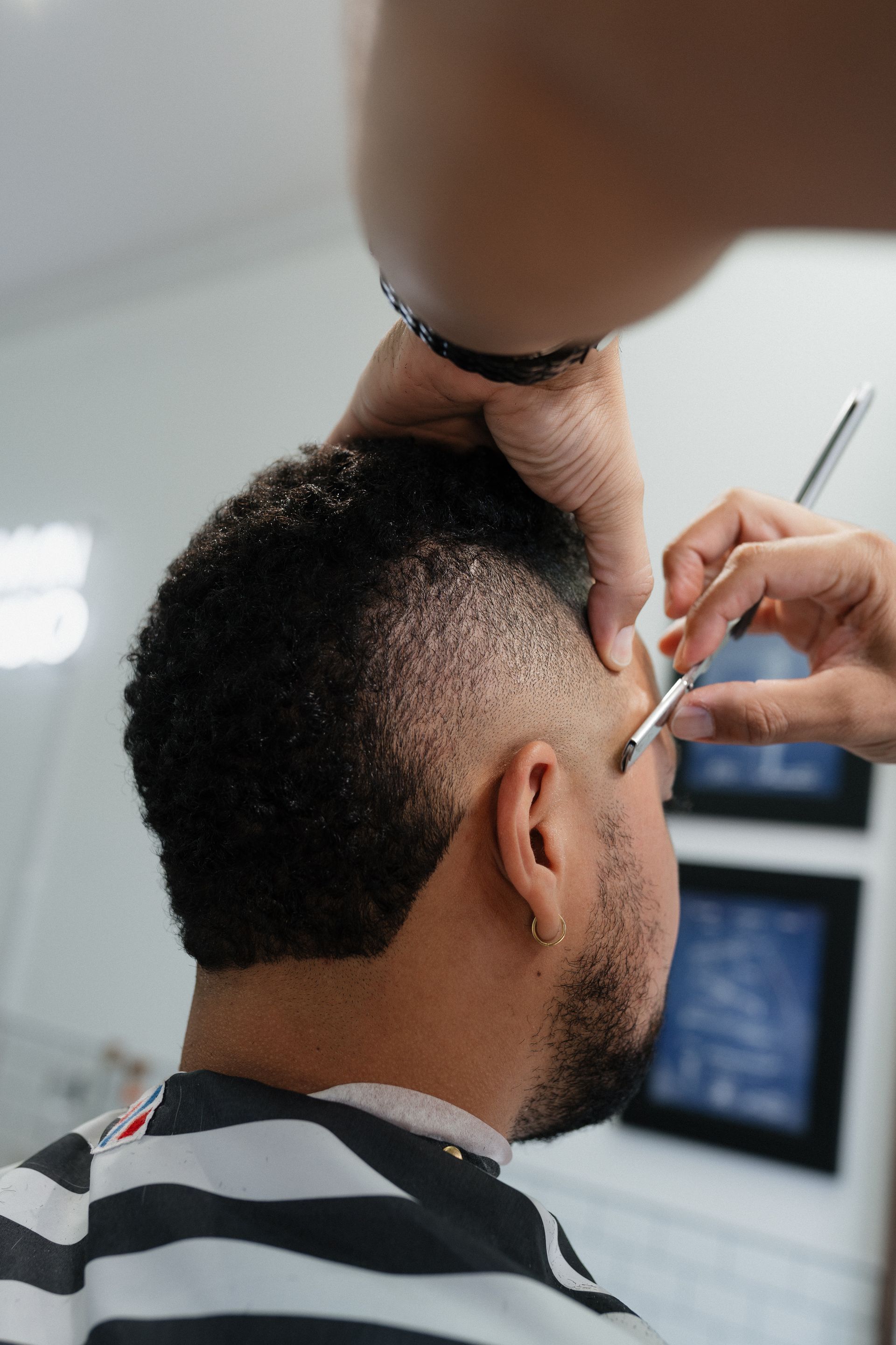 Barber shaping a fade and tidying brows at Modern Man Barber Studio in Long Branch, NJ.