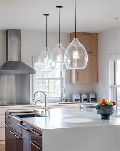 A kitchen with stainless steel appliances , a sink , and a bowl of fruit on the counter.