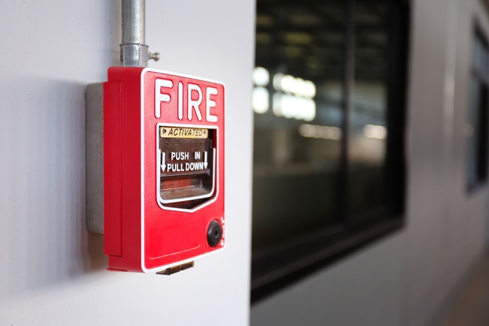 Red Fire Alarm Pull Station Mounted on A White Wall — Elibon Solutions in Garbutt, QLD