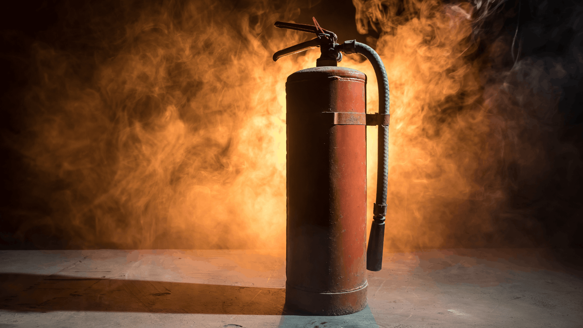 Red fire extinguisher against a hazy, orange-lit background — Elibon Solutions in Garbutt, QLD